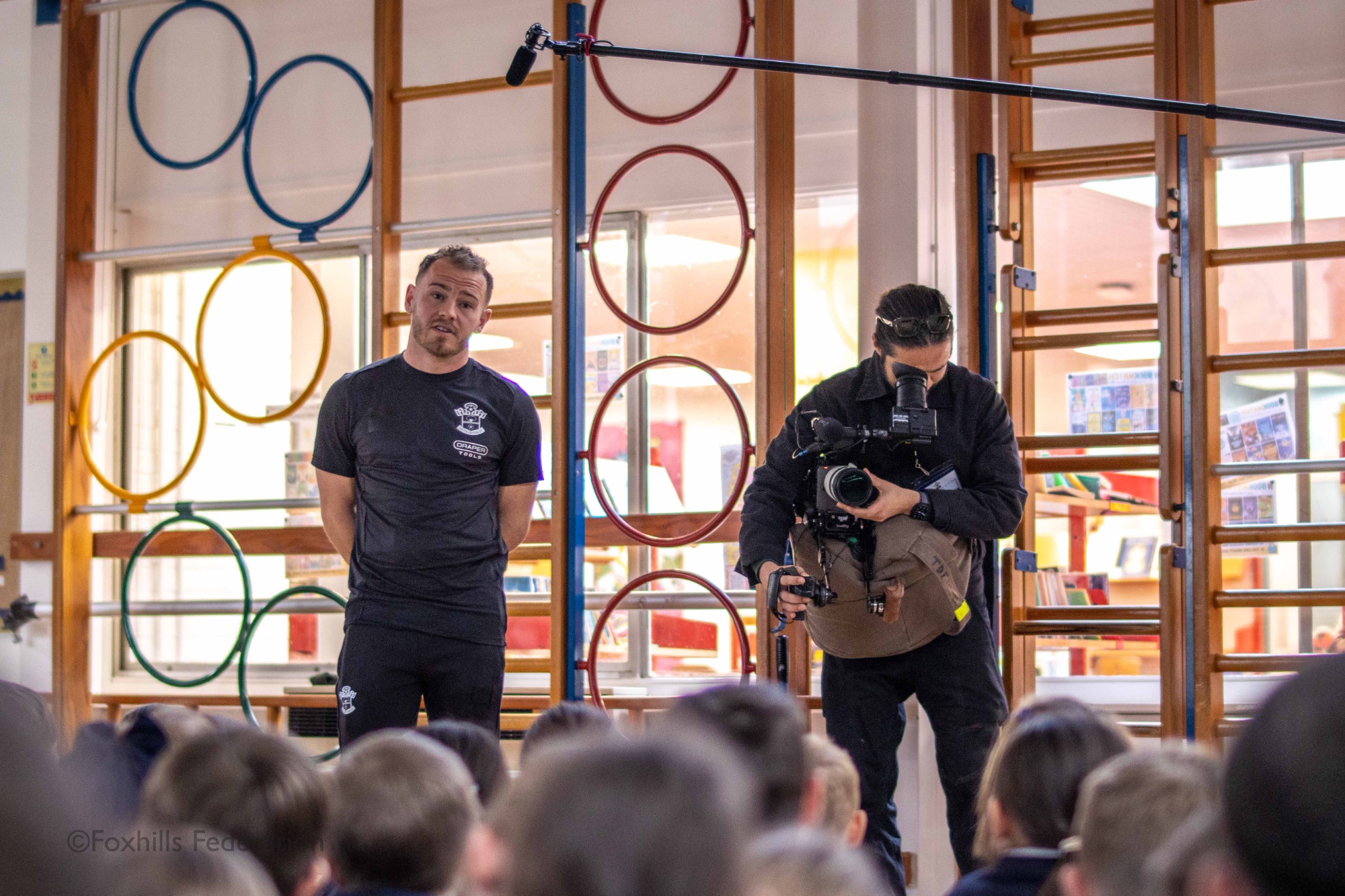 Premier League footballer, Ryan Fraser answers the children’s questions on his career while being filmed by a documentary crew.