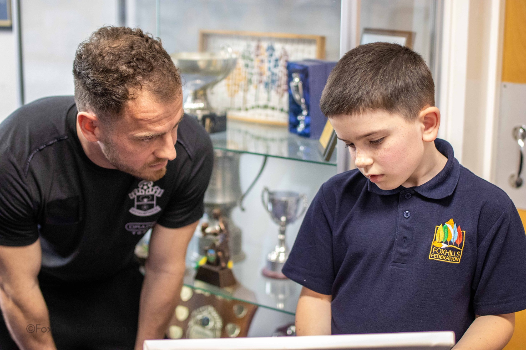 Jacob from year 4 shows Ryan Fraser a photo of his Great-grandad footballer.